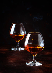 Grape brandy in shot glass, dark brown background, selective focus