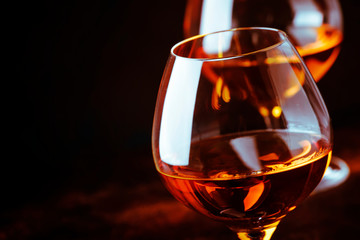 Grape brandy in shot glass, dark brown background, selective focus