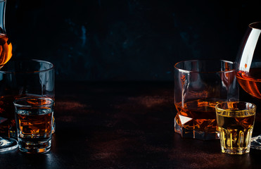 Selection of strong alcoholic drinks in glasses and shot glass in assortent: vodka, rum, cognac, tequila, brandy and whiskey. Dark vintage background, selective focus - obrazy, fototapety, plakaty
