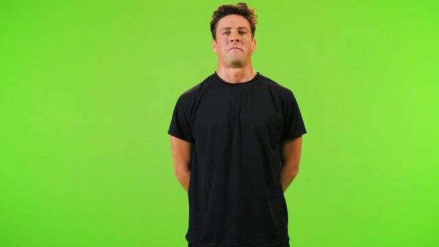 Soccer player posing, makes one step forward,  over a green screen. Medium shot.