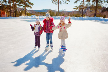 Three little girls skate on the ice. Vacations and holidays in nature