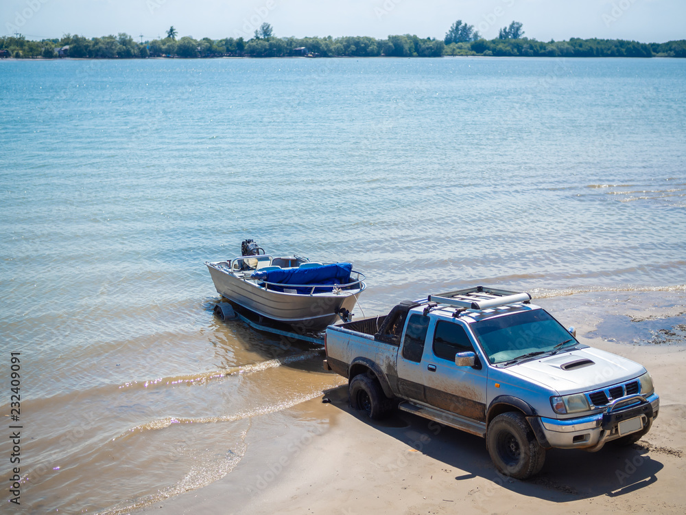 Wall mural motor boat being pulled with the pickup truck trailer on the beach