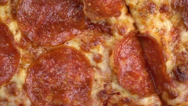 Sliced pepperoni pizza spinning video close up