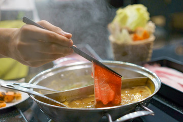 shabu shabu is a Japanese dish of pieces of thinly sliced beef or pork cooked quickly with vegetables in boiling water and then dipped in sauce. Hot Pot buffet asian cuisine.