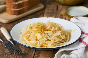 Sauerkraut with onions in a bowl on a wooden table