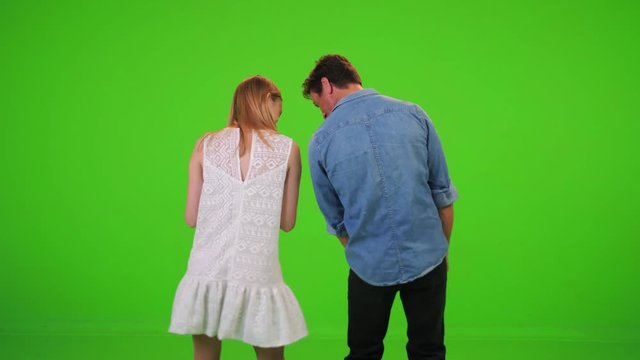 An excited couple dances in a concert, show or a party. From the back over a green screen.