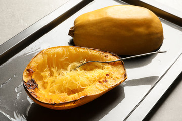 Baking sheet with cooked spaghetti squash and fork on table
