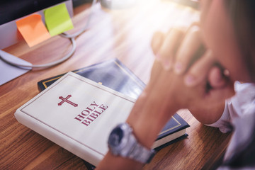 woman praying on holy bible before working in the morning