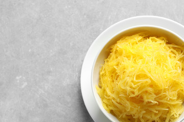 Bowl with cooked spaghetti squash on grey background, top view. Space for text