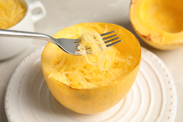 Fork with flesh over cooked spaghetti squash on plate