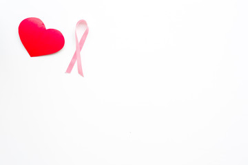 Breast cancer. Mammalogy concept. Symbolic pink ribbon near heart sign on white background top view...