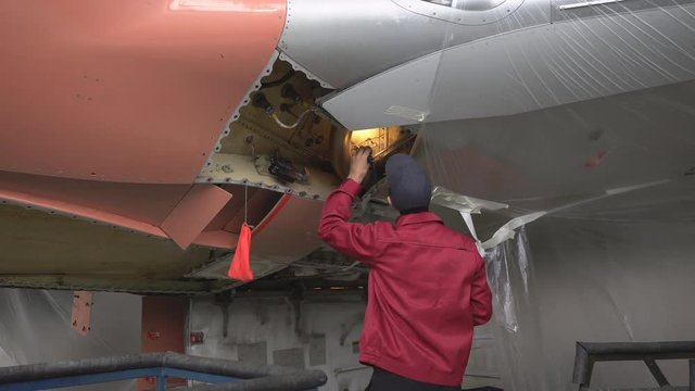 The engineer repairing the aircraft at the factory. Repair of an aircraft wing. Inspection of the fuselage. Passenger plane in the hangar in the repair. Aviation. 4K