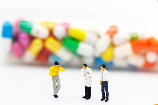 Miniature people: Patients standing with doctor and drugs. Health care and business concept.
