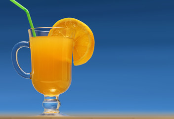 Glass of fresh orange juice with lemon slice and green drinking straw on blue