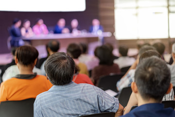 Rear view of Audience in the conference hall or seminar meeting which have Speakers are Brainstorming and talking on the stage, business and education about investment concept