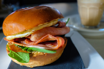 Breakfast bacon and egg roll with spinach and cafe latte coffee in the background