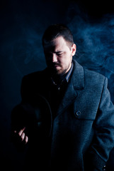 Fototapeta premium portrait of a man in a black coat on a dark background, Studio photo