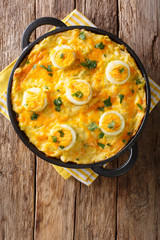 The traditional Welsh dish of Anglesey Eggs cooked from boiled potatoes, leek cheese sauce, and eggs close-up. Vertical top view