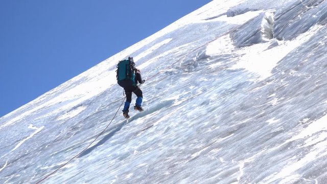 Side view of a male mountain climber going up icy slope with rope