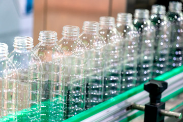 The new plastic bottles on the conveyor belt at the drinking water factory. Drinking water manufacturing process.
