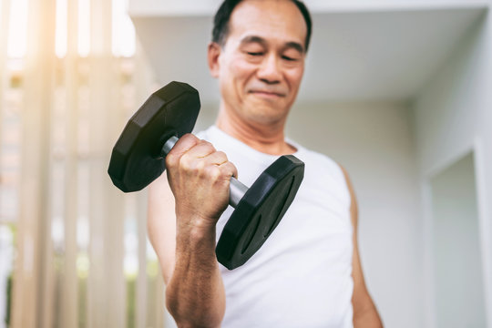 Senior man lifting dumbbell in fitness gym. Senior healthy lifestyle.