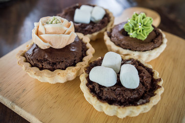 Close-up of Assorted mini brownie tart serving on the wooden table.