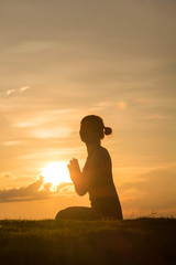 Young woman practicing yoga on the park at sunset, Silhouette