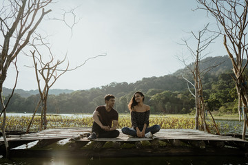 couple sitting on a floating wooden board on a lake