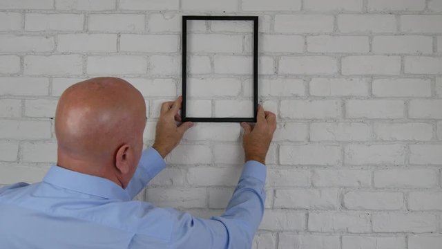 Businessman In Office Room Try to Find a Position on the Wall for a Frame