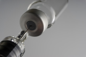 Medical syringe and vial on dark background with selective focus and crop fragment