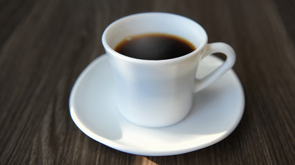 Black hot coffee on table with sunlight, relaxation concept and soft focus idea