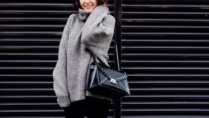 Outdoor fashion woman with trendy fall outfit, gray sweater and bag.