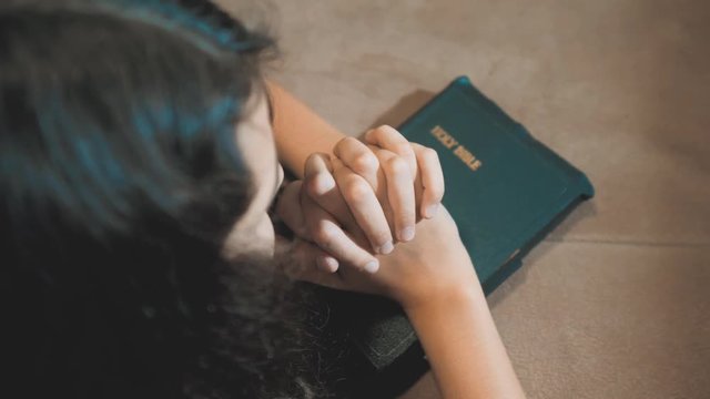 Little girl praying in the night. Little girl hand praying. little girl holy bible prays with bible in her hands. the catholicism sacred holy bible . children and religion upbringing faith symbol