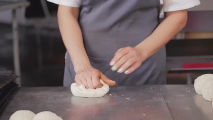 Baker's hands make bread on the table out of pieces of dough. Baking, tradition. Bread industry.
