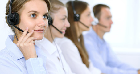 Call center operator in headset while consulting client. Telemarketing or phone sales