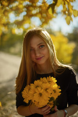 portrait of young woman in autumn park with flowers