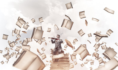 Handsome violinist sitting on book and play his melody