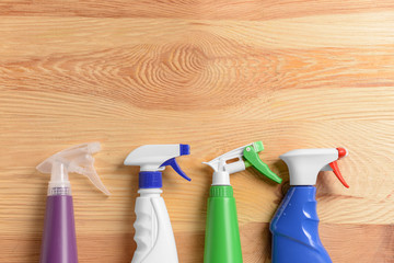 Bottles of cleaning detergents on wooden background