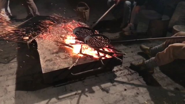 25-10-18 Zocca, Italy - Chestnuts festival: group of friends cooking chestnuts on a bonfire in slow motion.