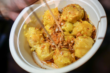A yellow steamed dumpling topping with fried garlic put in the paper cup. At Bangkok Thailand foodstruck streetfood.