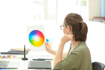Beautiful young designer working with color palette in office