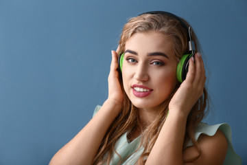 Beautiful young woman listening to music on color background