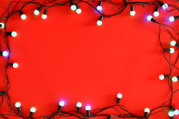 Christmas lights on red background, top view