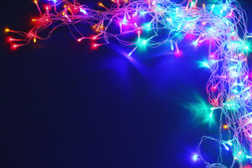 Christmas lights on blue background, top view