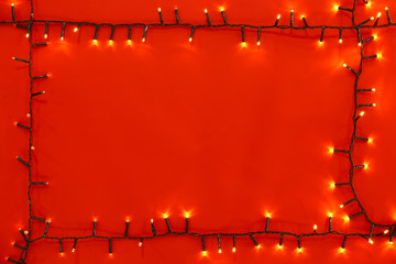 Christmas lights on red background, top view