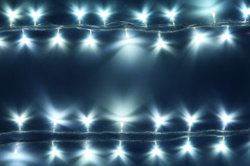 Christmas lights on blue background, top view