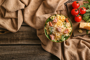 Delicious pasta with sausage in bowl on wooden table