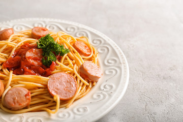 Plate with delicious pasta and sausage on grey table