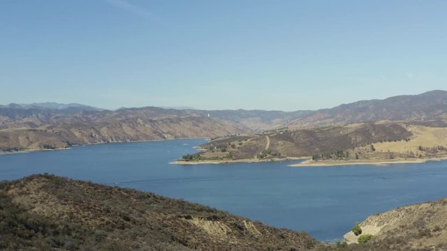 A blue lake in between hills with power boats and kayaks