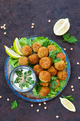 Homemade falafel made from chickpeas, on salads. Dark background.